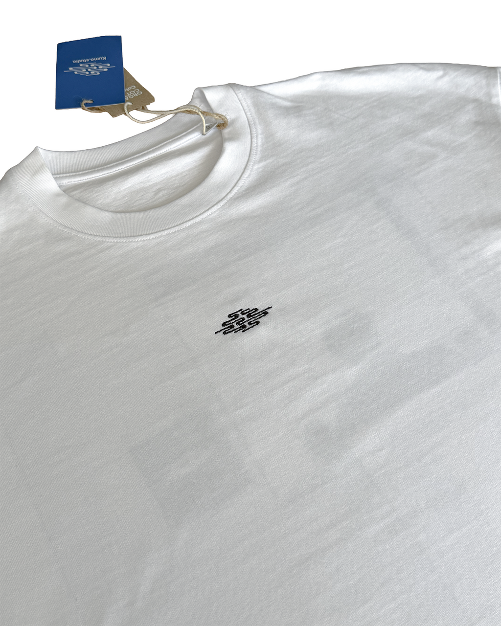 T-shirt en coton, il présente une illustration originale pensée comme une planche de manga, imprimée en DTF, racontant le parcours d'un salaryman qui découvre, dans le métro tokyoïte, une mystérieuse annonce de recrutement. Cette dernière le conduit jusqu'au siège de la Kumo.Company. En réalité l'annonce est celle du pop-up de présentation de la collection Spring / Summer 2026.
